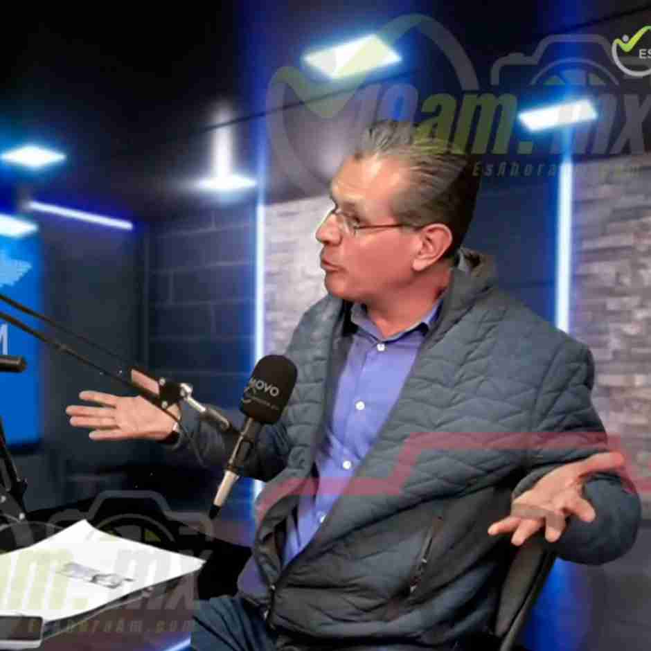 Alejandro Delgado Scoy en un estudio de radio, hablando al micrófono y gesticulando con las manos, con luces azules al fondo.